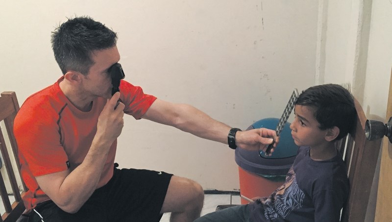 Tom Wilk performs an eye exam on a young Costa Rican during his recent trip to the South American country.