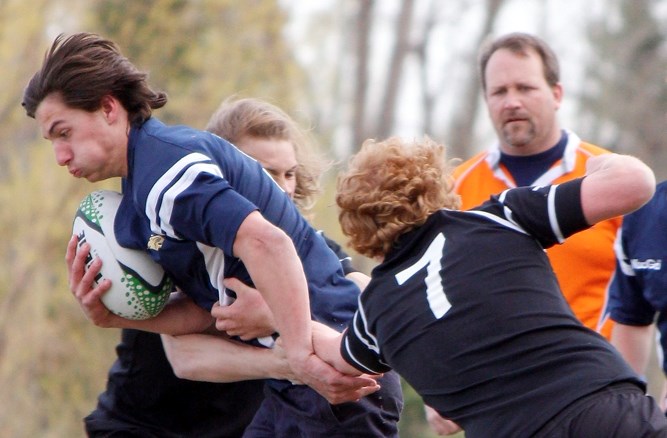 Cochrane Rugby&#8217;s Jakob Kromrey breaks through two Holy Trinity Knights tacklers in Big Sky Rugby Union high school senior boy&#8217;s play April 29 in Okotoks. Knights