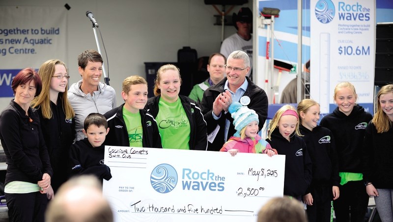 Mayor Ivan Brooker accepts a cheque for the cause from the Cochrane Comets swim club for $2,500 at the town&#8217;s Rock the Waves celebration May 8.