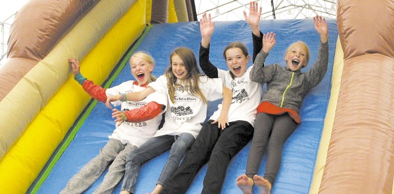 From left: Sydney Horrocks, 12, Courtney Head, 11, Carys Peppinck, 11, and Wren Horrocks, 10, of Calgary slide down an air-inflated play structure at Springbank Park For All