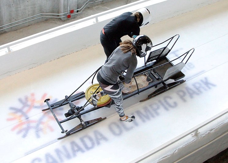 Christine de Bruin and Cochrane&#8217;s Janine McCue ride a practice sled back up to the start during training at WinSport Winter Sport Institue in Calgary. The female,