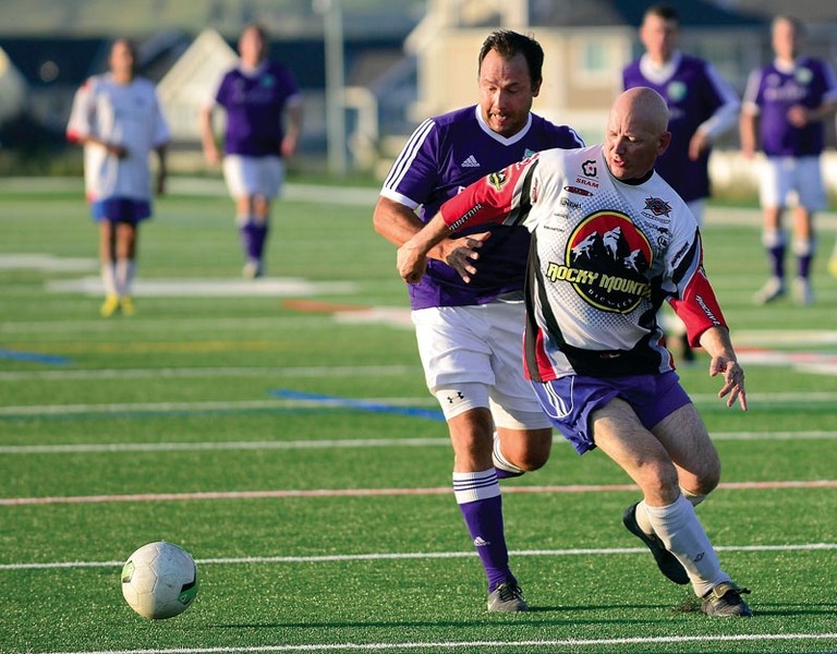 Cochrane Soccer Club&#8217;s Justin Kerr (rear) challenges for the ball in Calgary United Soccer Association Masters 3 men&#8217;s play vs. Hoods United Over-35 at Spray Lake 