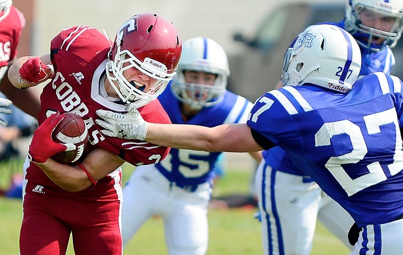 Cochrane Cobras running back Ethan Forrest protects the ball from Central Catholic Cougars defender Kahl Stickel in high-school exhibition football play Aug. 29 at Cochrane