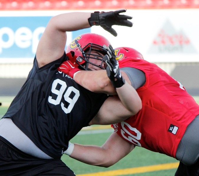 Cochrane High School Cobras 2015 grad Aidan Smith (left) locks up with University of Calgary Dinos senior offensive lineman Sean McEwen during Dinos&#8217; Aug. 31 practice