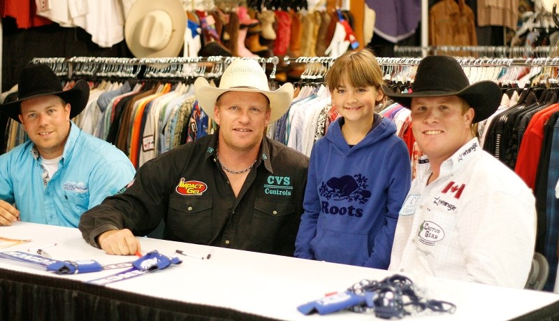Steer wrestlers Dayton Roworth of Czar (from left) Travis Reay of Mayerthorpe and Cochrane&#8217;s Tanner Milan sign autographs for 10-year-old rodeo fan Lauren Oblak at the