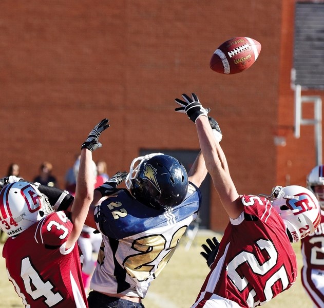 Cochrane High School Cobras Jackson Carter (left) and Joel Quennell break up a pass intended for Bow Valley Bobcats receiver Nathan Hillier on Oct. 17 at Cochrane High.