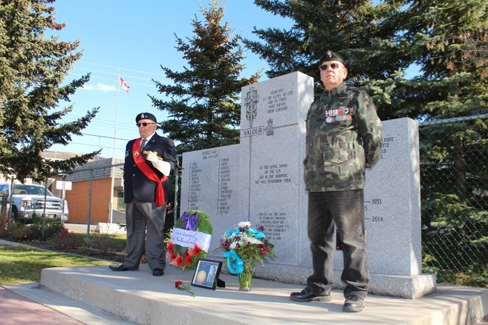 Steve Merritt (left) and Brian Walford hold a vigil at Cochrane cenotaph for Cpl. Nathan Cirillo on Oct. 22, a year after the Canadian Armed Forces corporal was gunned down