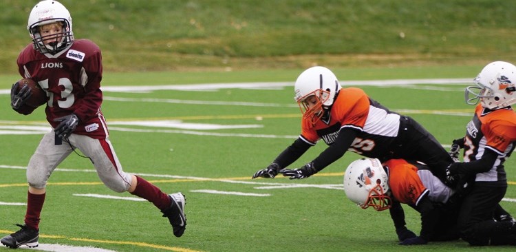 Cobras Lions player Ethan Clazie (left) avoids three Mavericks players to score a touchdown on Nov.1. The victory meant the Cochrane Lions Atom team went their entire
