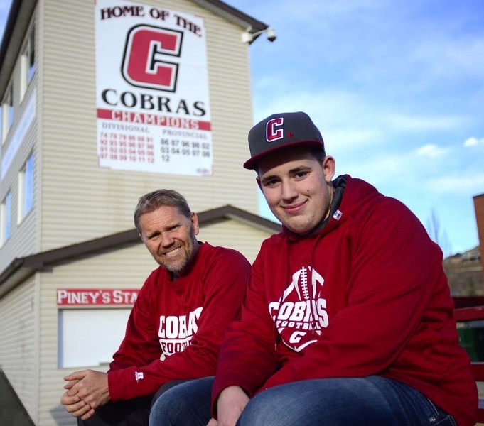 Cochrane High School football coach Rob McNab and player Cody Pickering sit out front of the school&#8217;s Vern Friesen field house Nov. 17. Pickering was taking equipment
