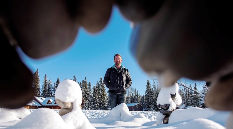 Calgarian Luke Materi is framed by one of the structures he&#8217;s building in his “;Winterfell”project along the Elbow River in Bragg Creek.