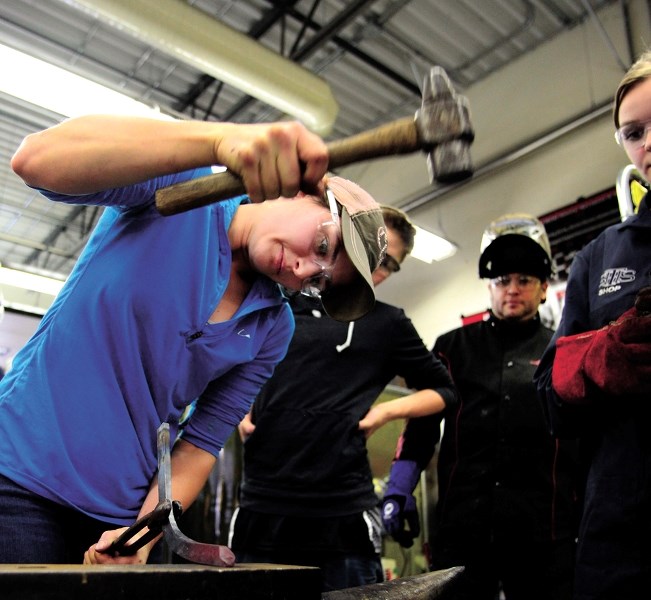 Instructor Lynn Fleury shows St. Timothy High School students Kennedy Michalski, Shanice Nkatchazo, and Delaney Weibe some of the tools used for farrier services in