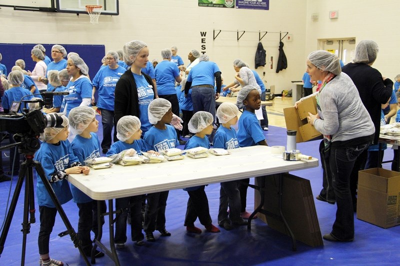 Bearspaw Christian School youngsters get ready to load the meals they prepared into a box during the school&#8217;s Feed the Need initiative Dec. 11. Three-hundred of the