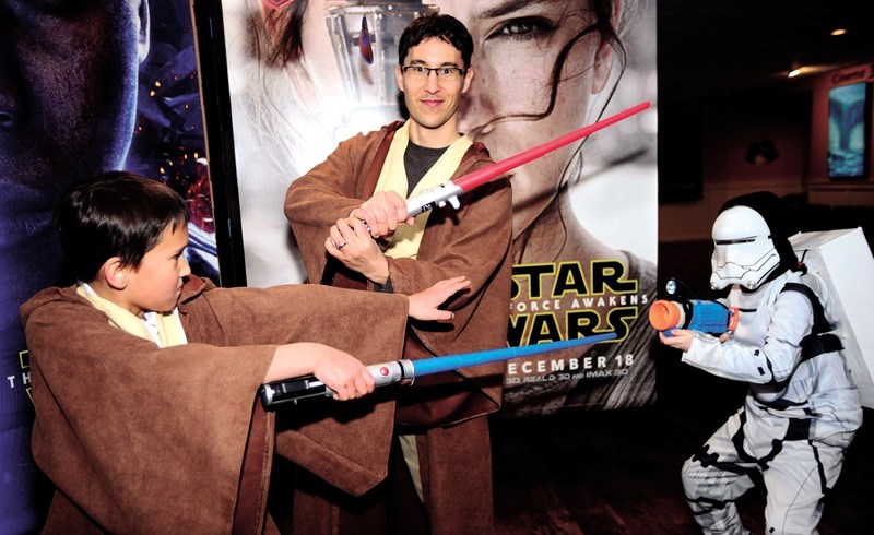 Riley Kariatsumari (left) and his Jedi father Bob take on a Storm Trooper played by Joseph Shaw. Star Wars: The Force Awakens was sold out in advance for the Dec. 17 red