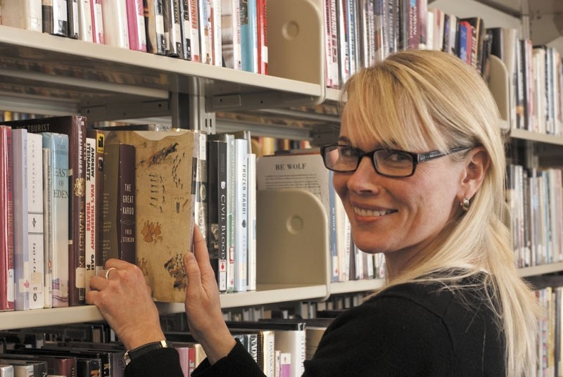 Jennifer Burnell, a public services assistant at the Library, stocks books. The library is one project the Rotary club has heloed with over the years.