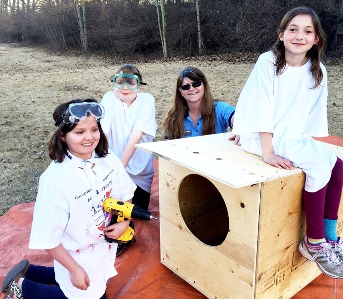 The Cochrane Girl Guides constructed dog houses to help the Humane Society. Left: Guides Molly Tuck, Molly Bridle, guide leader, Marion Phillips, and Danica Richter pose with 