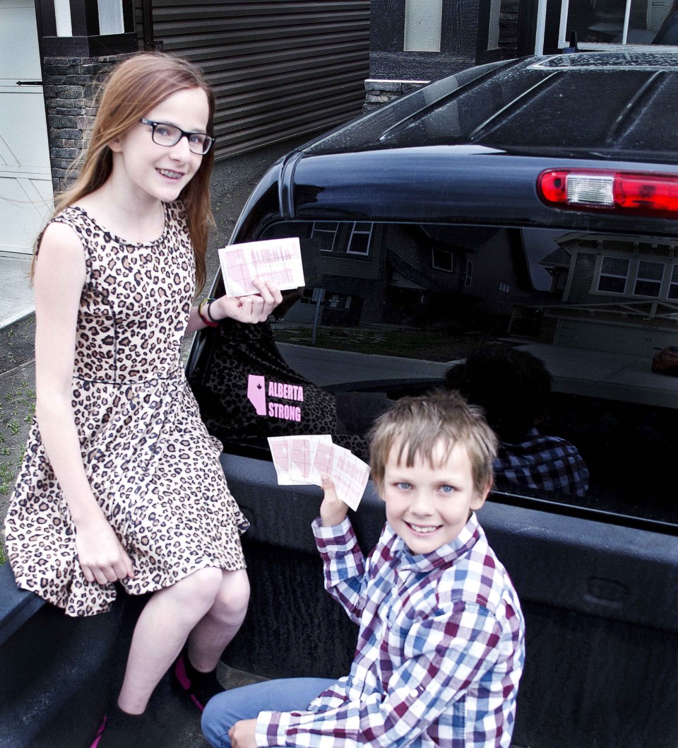 Teeghan, 12, and Logan, 10, Cherrington showcasing the Alberta Strong decals for sale, asking a minimum donation of $5 to be donated to Red Cross to help the wildfire