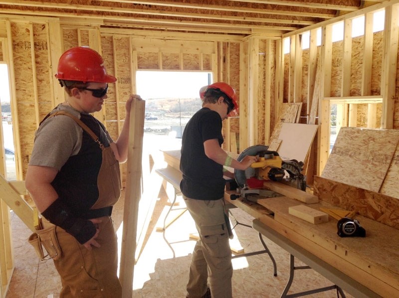 Anthony Archer works at the chopsaw while Patrick Hardiman &#8220;supervises.&#8221;