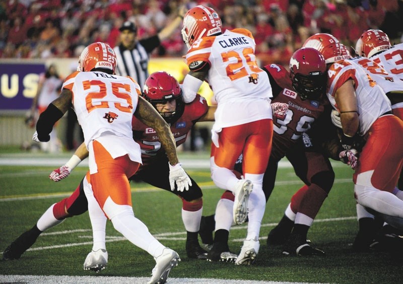Cochranite and Calgary Stampeders running back Rob Cote (left) tries to hold off two B.C. Lions players during his team&#8217;s epic 44-41 overtime win on July 29 at McMahon