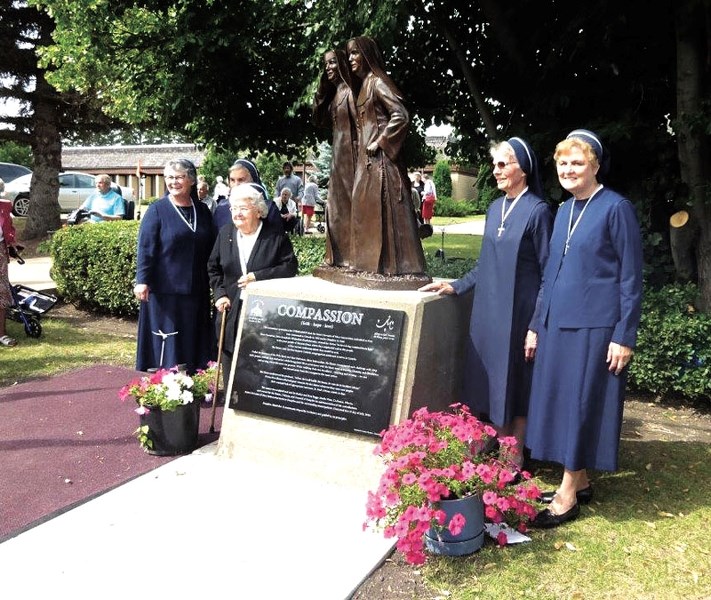 Sisters Servants of Mary Immaculate members pose with, Compassion, a bronze statue cast by Studio West Foundry and Art Gallery, which was commisioned by the town of Dauphin,