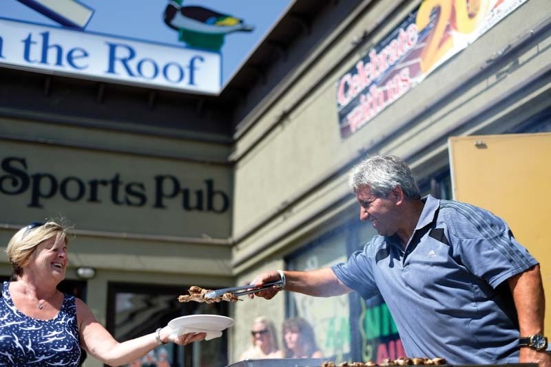 Owner John Scondrianis dishes out souvlaki at a Ducks on the Roof barbecue.