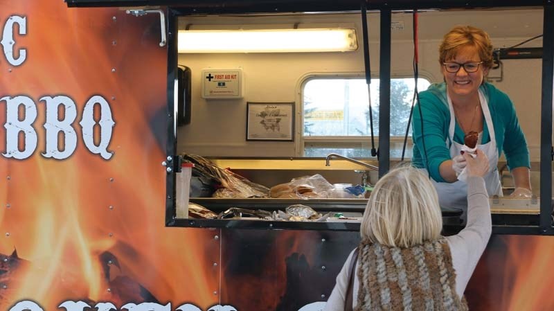 Luella Anderson of the Broken Smoke food truck hands a piece of chicken to a happy customer.