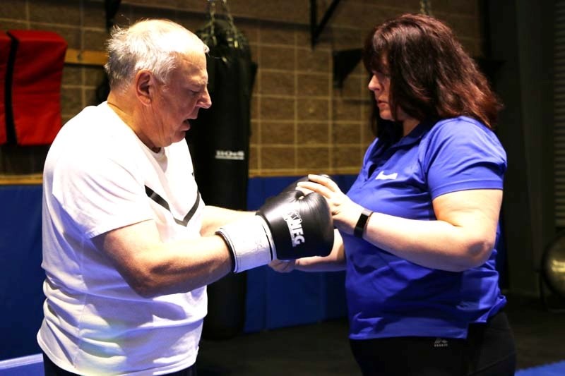 Don Mytrash is helped into boxing gloves by Jo-anne Paulgaard.