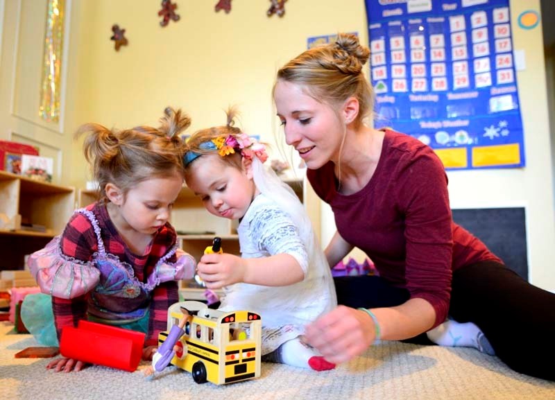 Childcare professional Jessica Walker plays with Siena Reade and Autumn Braaten during play time.