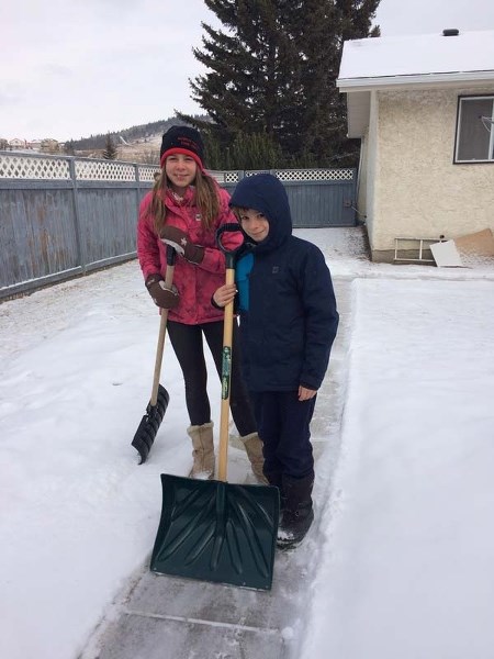 Hannah, 11, left, and her brother Thomas, 9, shovel the back walk for their neighbourhood match, Madge Weskow, in Cochrane, Alberta.