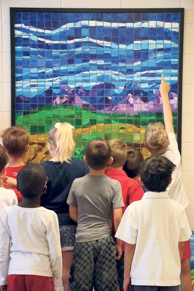 Students gather round and point out the tiles they each painted at the May 29 unveiling of a legacy mosaic at Elizabeth Barrett Elementary School.