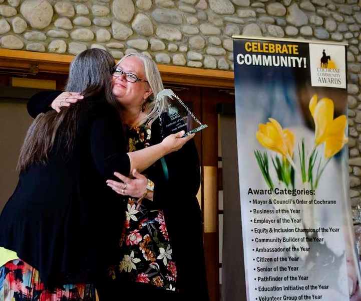 Anita Wildman (right) hugs Cochrane Community Awards organizer Valerie McCracken as Wildman accepts the Pathfinder of the Year Award for her late husband Cody Wildman at the