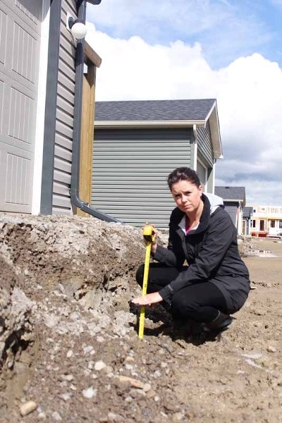 Kendra McDonald of 169 Willow St. holds her hand up to around where the asphalt paving will come to once Volker Stevin finishes paving in the coming weeks. As far as she and