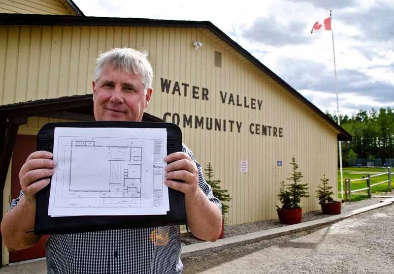 Vice president of the Water Valley Community Association Harold Baxandall shows the plans for the new Water Valley Community Centre in front of the original 1942 hall on May