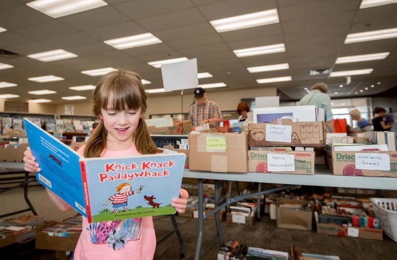 Clara Halkyard, 6, reads a rhyming book at the annual Beyond Words Book Sale at the Nan Boothby Memorial Library in Cochrane on Saturday, June 3, 2017.