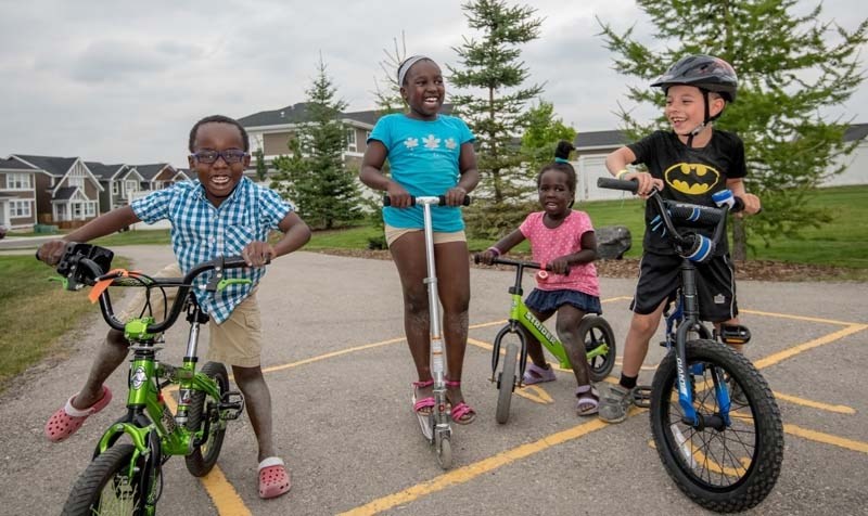 Siblings Matthew Rwothumio, 6, Abigail Uyungrwoth, 8, Blessed Rwothumara, 3, play with friend Naveed Andrade, 7, at Riversong Park in Cochrane on Aug. 1.