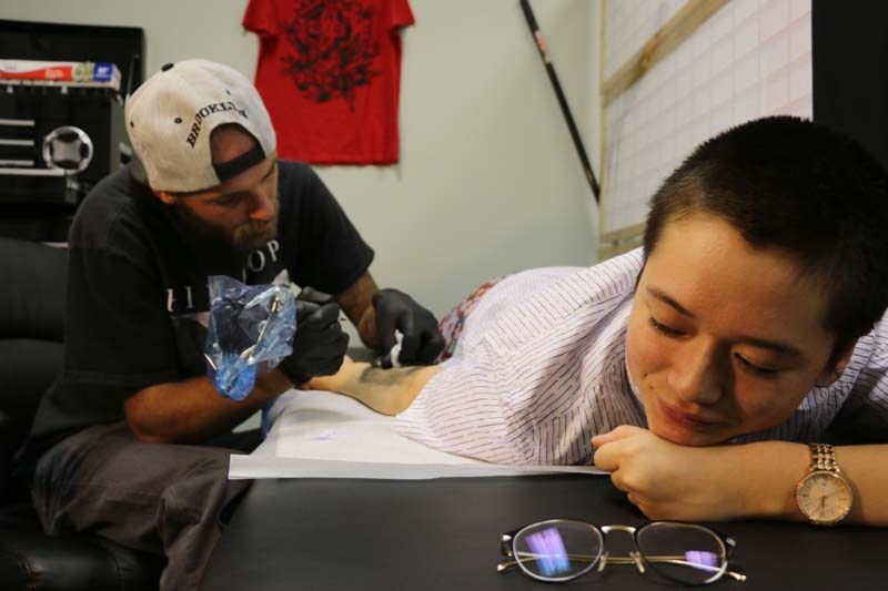 Hanako Rodgers relaxes while she gets her flash tattoo as part of Sink or Swim Creations&#8217; Camp fYrefly fundraiser.