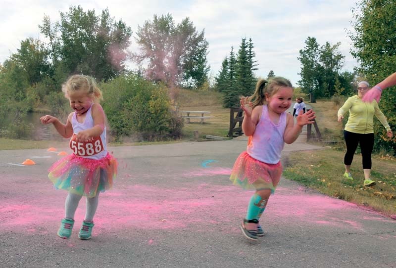 Camille Jackson (2) and Marley Smith (3) get blasted with pink powder at Cochrane&#8217;s first annual Vaughn&#8217;s Memorial Colour Run on Sept. 3.