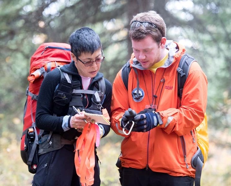 Cochrane SAR member-in-training Karen Woo and Alex Chapman discuss their position during the field assessment phase of SAR training north of Cochrane on Saturday.