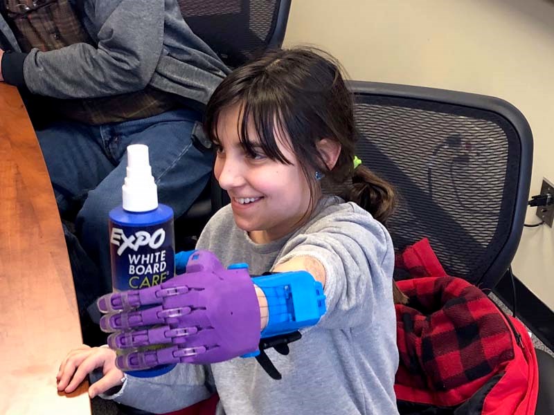 Jerlena Rittwage picks up an item with her new hand for the first time. On Jan. 17 two Cochrane High School students presented to Rittwage the prosthetic hand they made using 