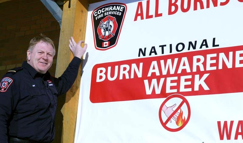 Jeff Avery poses with the new National Burn Awareness Week banner hanging outside the fire station. A new banner will be hung each month to spotlight the fire crew&#8217;s