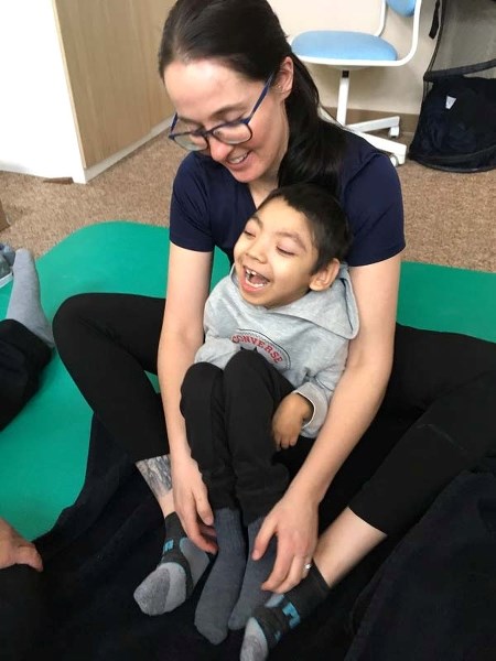 Theinen Holloway Daniels, nearly 11, enjoys a session with Dawn Armstrong, a contracted physiotherapist who may face lay off by Williams Consulting. Armstrong worked two days 