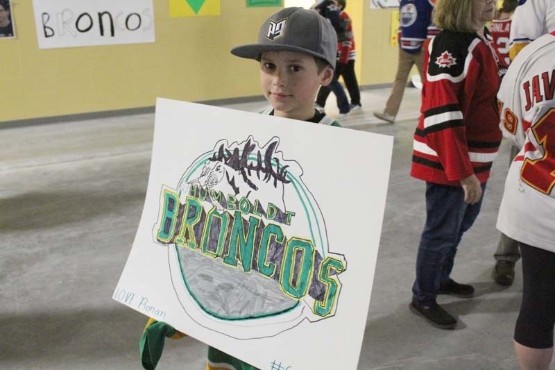 Nine-year-old Ronan Neutens holds up his freehand banner depicting the Humboldt Broncos team logo.