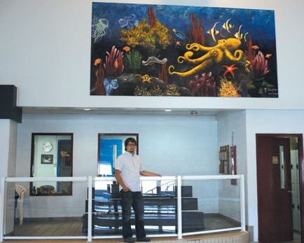 Big Hill Leisure Pool manager John Napier proudly poses under the new mural on display in the pool area, painted by Taygan Crapo and Hayley Eidet.