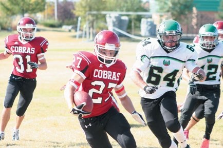 Cochrane High School Cobras receiver Nik Noseworthy tries to escape the oncoming tackle of Springbank Phoenix defender Alex Evans in Rocky View Sports Association football