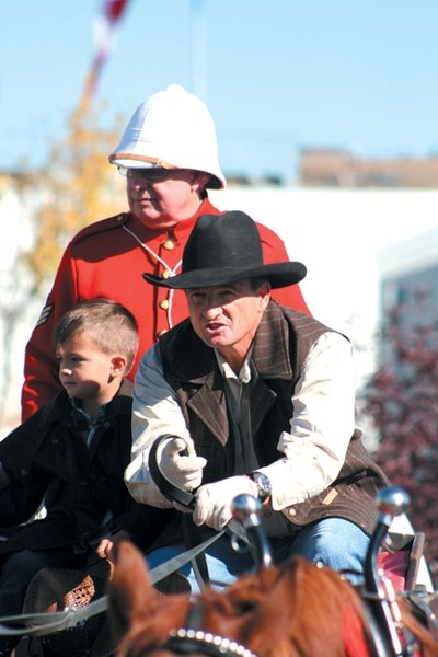 Richard Benedictson (RCMP apparel), Alex Baum and his four-year-old nephew, Alex Beckett, bring the pennies down Fifth Avenue to ATB Financial via horse-drawn wagon for the