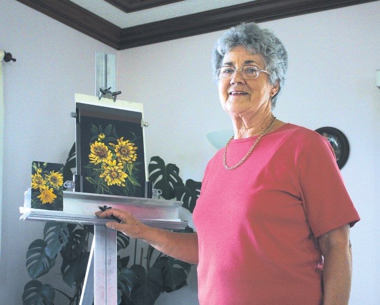 Foothills Art Club member, Janette Whittle, stands with her latest piece, her pastel depiction of a trio of calendulas.