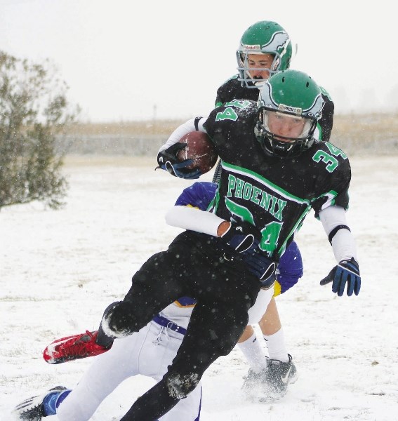 Springbank Community High School Phoenix running back Kevin Demmers is grabbed by Bert Church High School Chargers defender Clayton Johnson in Rocky View Sports Association