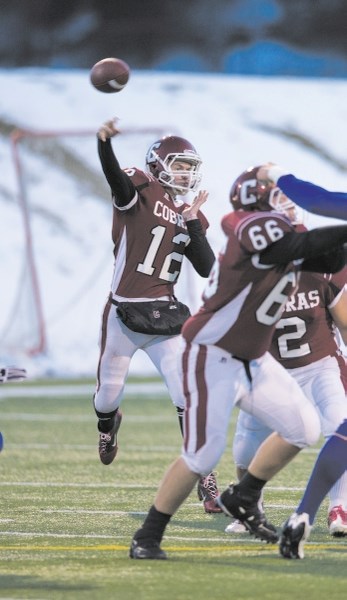 Cochrane Cobras quarterback Cody Stevens fires the ball as offensive lineman Bryce McKinnon helps keep Winston Churchill Bulldogs defenders out of the way in Tier 3