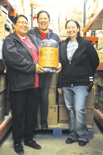 From left: Adele Rabbitt and Belinda Simeon of the Nakoda Food Bank and Nora Lee Rear of the Eagle&#8217;s Nest Family Shelter have been placing these jugs all over Cochrane