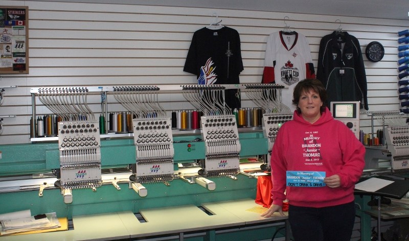 Shannon Dyck, owner of Shannon Designs-Embroidery and Promotions, displays a hooded sweatshirt and bumper sticker she is selling in memory of Brandon Thomas, the 17-year-old