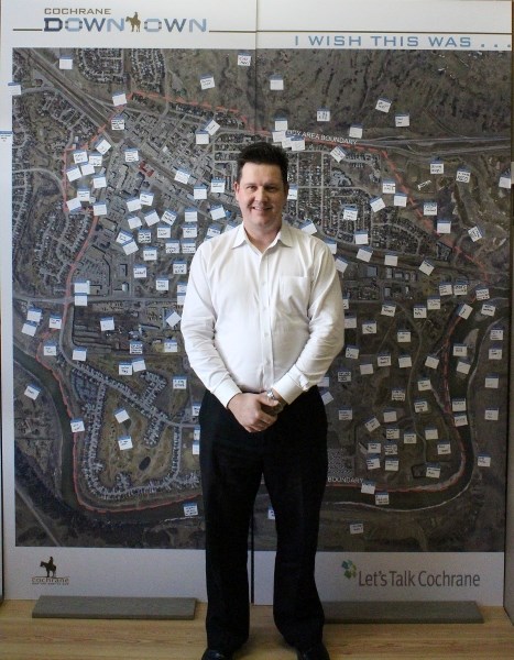Mike Korman, economic development manager for the town, stands before a poster of Cochrane&#8217;s downtown area where suggestions are being gathered as to what would be best 